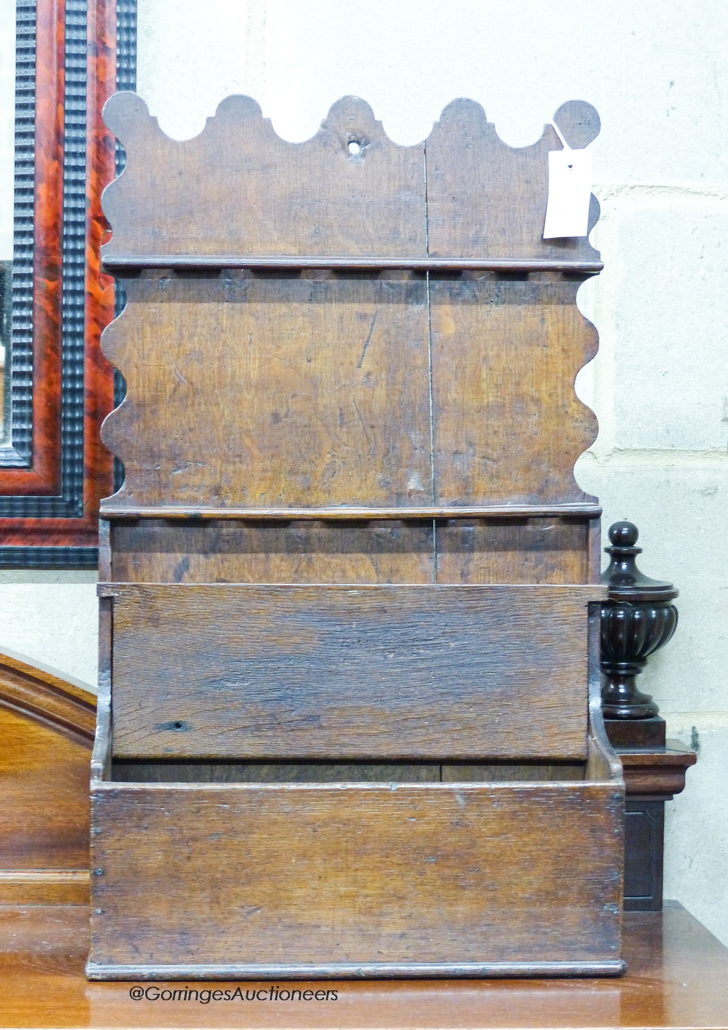 An 18th century oak spoon rack, of shaped outline with lidded compartment below, width 39cm, depth 14cm, height 66cm